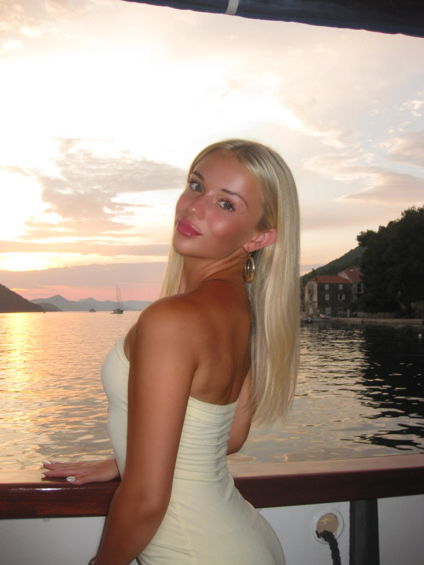 Teagan on a boat in a coastal bay at sunset