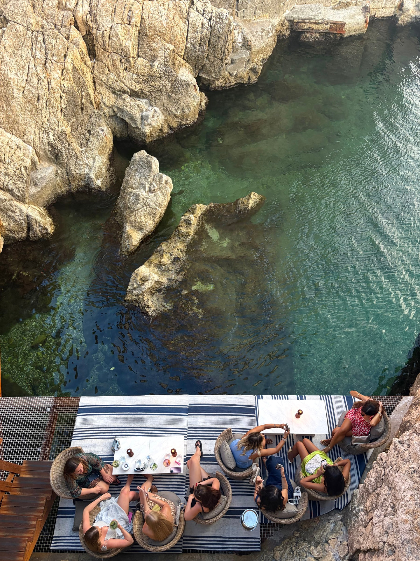 A group of friends relaxing together on a waterside club deck beside the sea