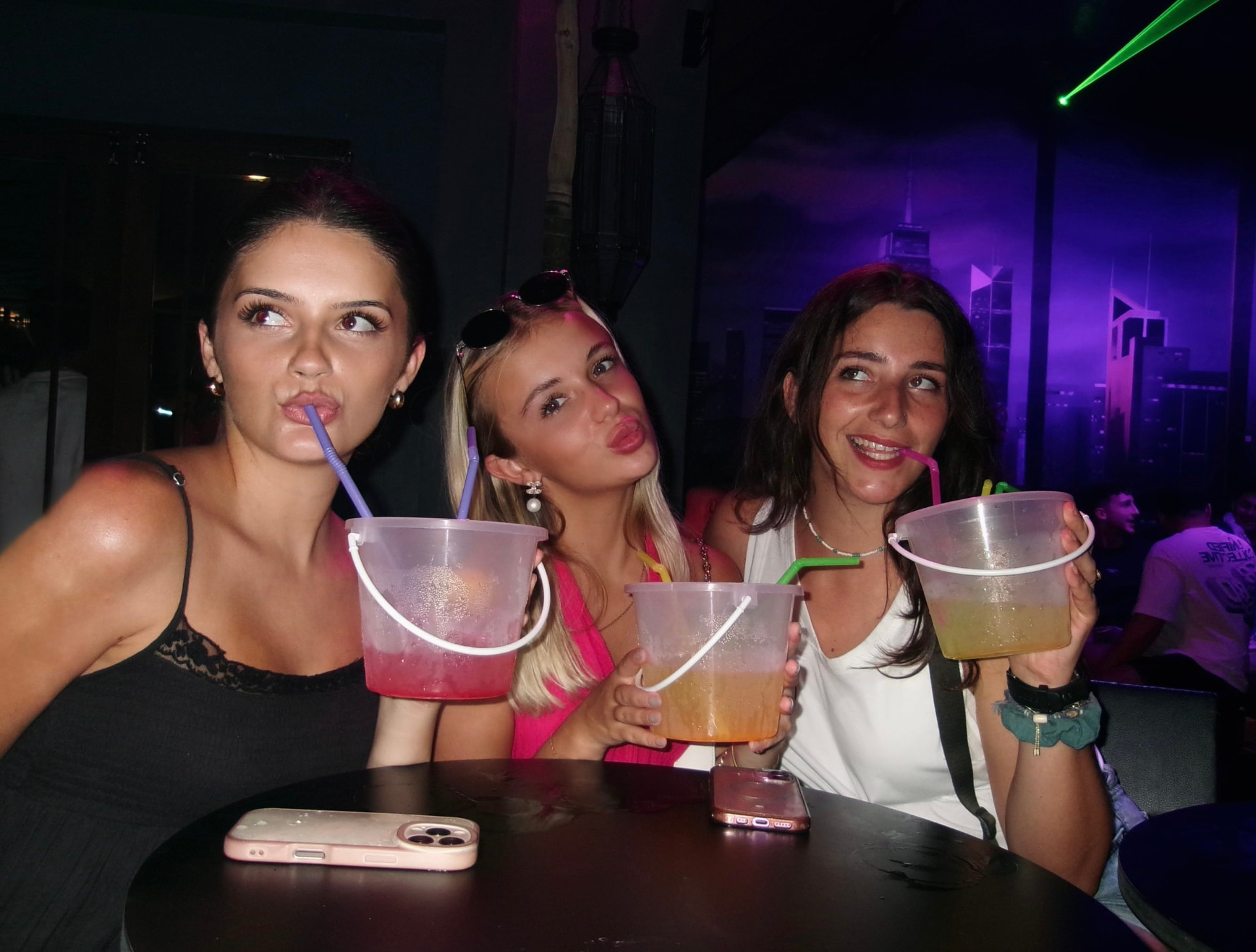 Friends holding colourful drinks together on a night out