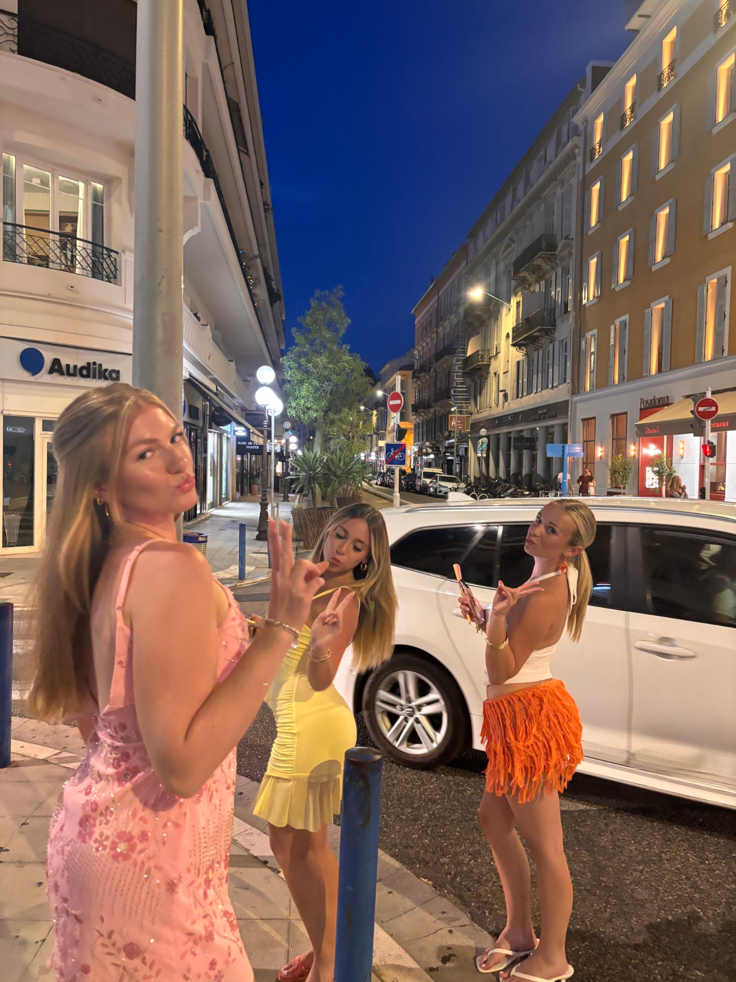 Three friends posing on a lamplit street in the evening